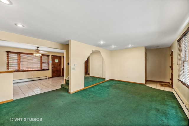 unfurnished living room with a baseboard heating unit, ceiling fan, light carpet, and a healthy amount of sunlight