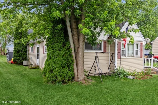 rear view of property featuring cooling unit and a lawn