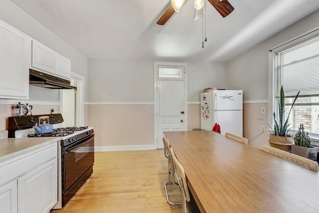 kitchen with white refrigerator, light hardwood / wood-style flooring, white cabinetry, and black range