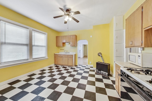 kitchen with light brown cabinetry, white appliances, ceiling fan, and sink