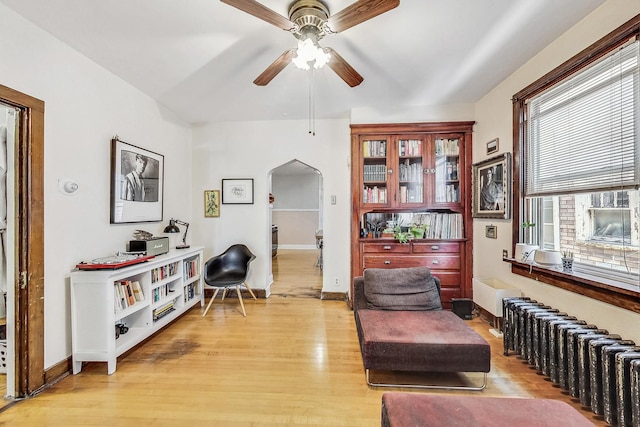 sitting room with ceiling fan, light wood-type flooring, and radiator