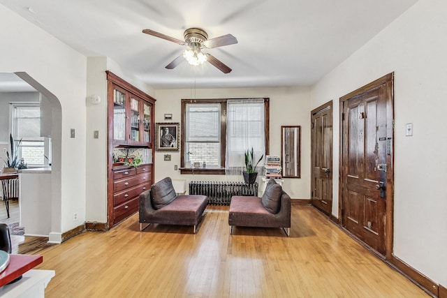 living area featuring ceiling fan, radiator heating unit, and light hardwood / wood-style floors