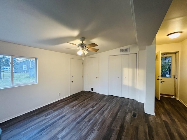 unfurnished bedroom with multiple closets, vaulted ceiling, ceiling fan, and dark wood-type flooring