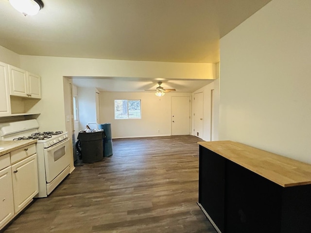 kitchen featuring white gas range, ceiling fan, dark hardwood / wood-style flooring, and white cabinets