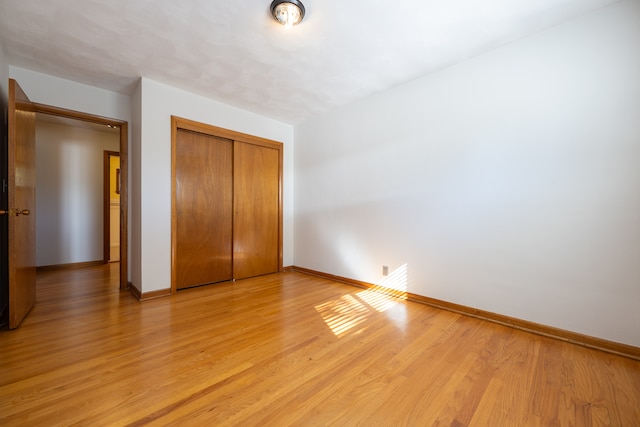 unfurnished bedroom with light hardwood / wood-style floors and a closet