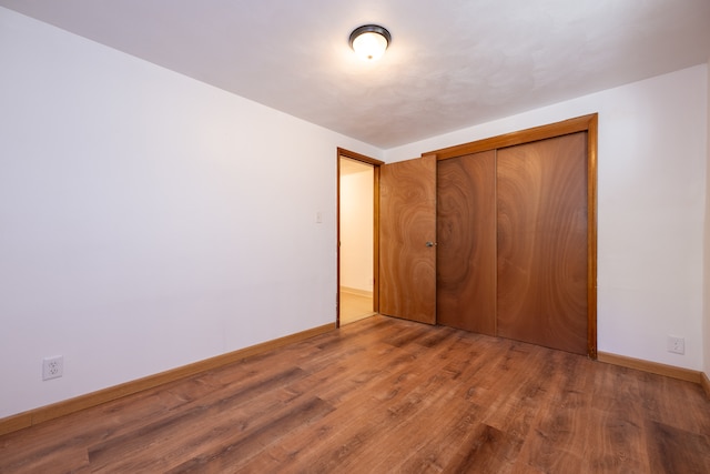 unfurnished bedroom featuring wood-type flooring and a closet