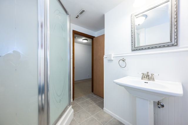 bathroom featuring an enclosed shower, wooden walls, and tile patterned floors