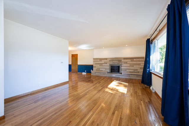 unfurnished living room featuring a stone fireplace and hardwood / wood-style floors