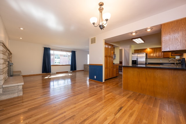 kitchen with appliances with stainless steel finishes, kitchen peninsula, a fireplace, and light wood-type flooring