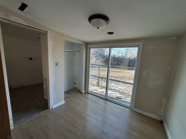 unfurnished bedroom with access to exterior, hardwood / wood-style floors, and a closet