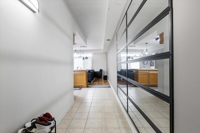 hallway with a notable chandelier and light tile flooring