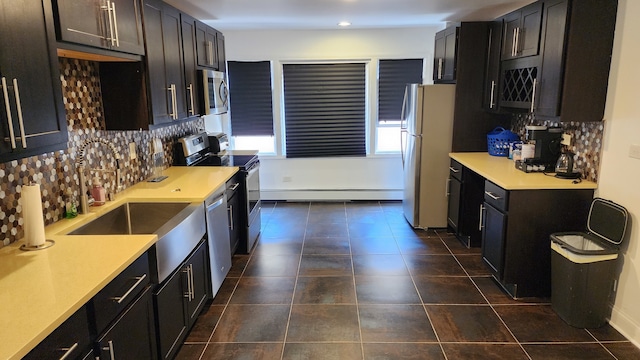 kitchen with stainless steel appliances, baseboard heating, dark tile floors, and tasteful backsplash