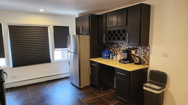 kitchen featuring a wealth of natural light, baseboard heating, tasteful backsplash, and fridge