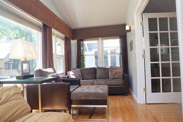 living room with light hardwood / wood-style flooring, lofted ceiling, and french doors