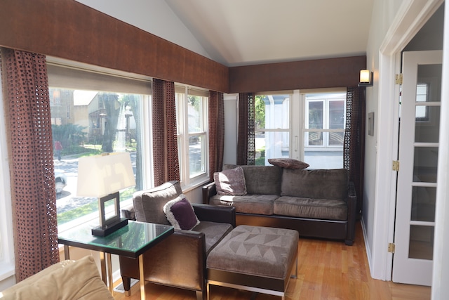 living room with plenty of natural light, lofted ceiling, and light wood-type flooring