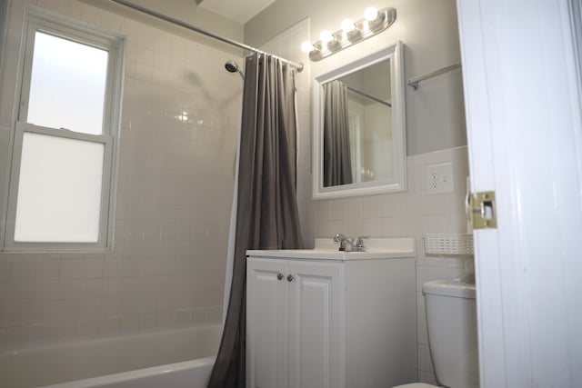 full bathroom with shower / bath combo, a healthy amount of sunlight, toilet, and tile walls