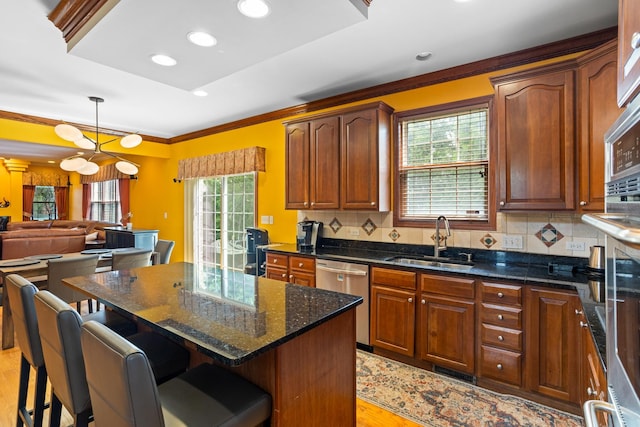 kitchen featuring stainless steel appliances, light wood-type flooring, hanging light fixtures, a kitchen island, and sink