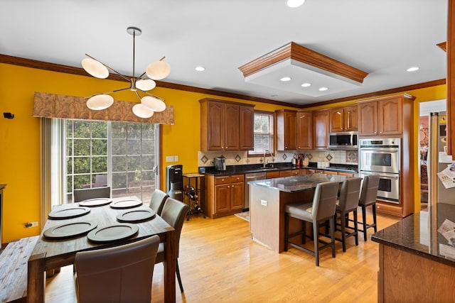 kitchen with appliances with stainless steel finishes, crown molding, tasteful backsplash, and a center island