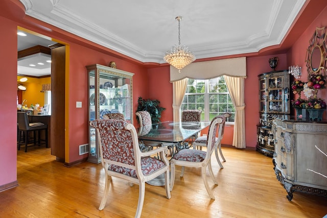 dining area featuring an inviting chandelier, ornamental molding, and light hardwood / wood-style floors