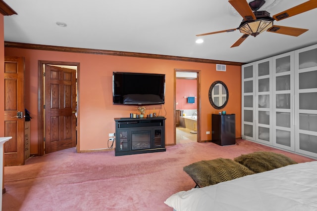 carpeted bedroom featuring ceiling fan, connected bathroom, crown molding, and a fireplace