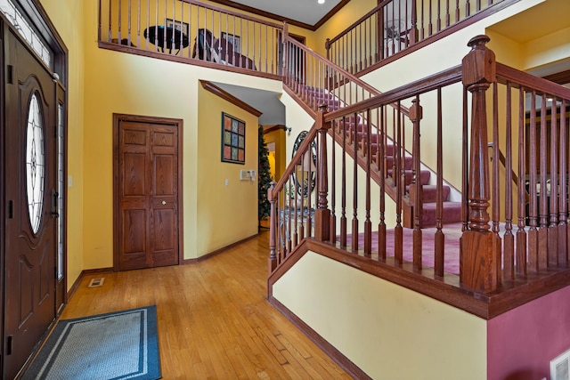 foyer featuring a towering ceiling, hardwood / wood-style flooring, and crown molding