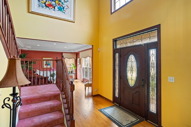 foyer entrance with light hardwood / wood-style flooring and crown molding