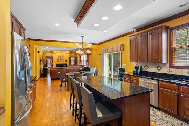 kitchen featuring stainless steel appliances, a center island, crown molding, a kitchen bar, and sink