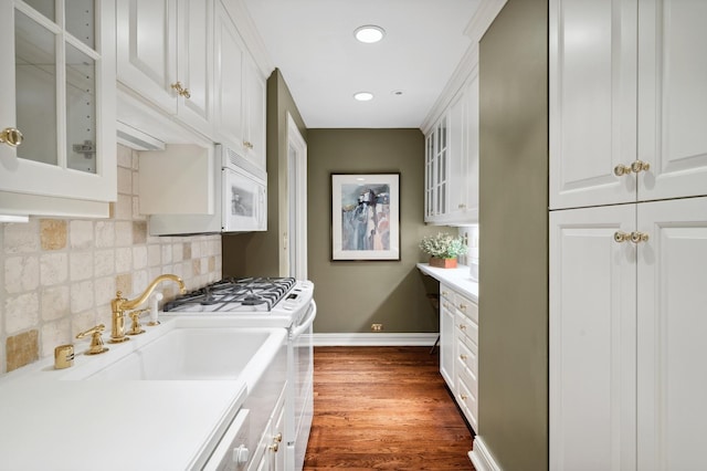 kitchen with dark wood finished floors, light countertops, white range with gas stovetop, baseboards, and glass insert cabinets