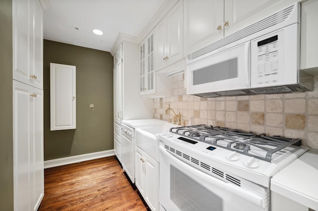 kitchen featuring backsplash, white cabinetry, glass insert cabinets, white appliances, and light countertops
