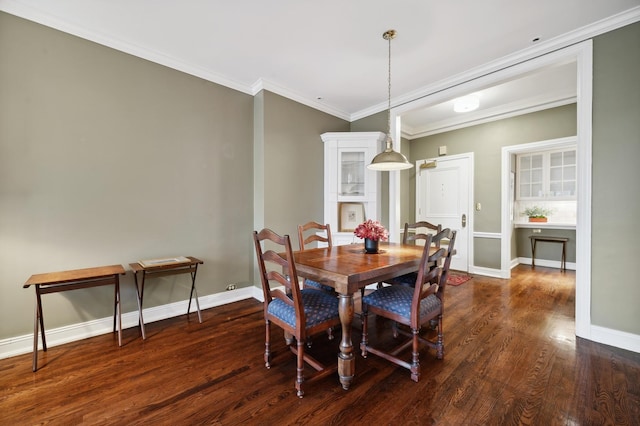 dining space with dark wood-type flooring, crown molding, and baseboards