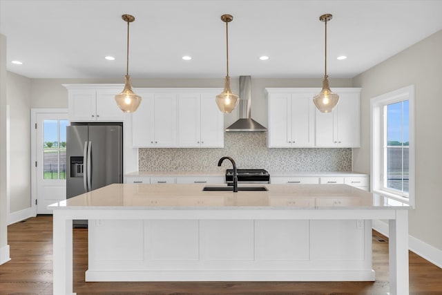 kitchen featuring dark hardwood / wood-style floors, tasteful backsplash, a center island with sink, pendant lighting, and wall chimney exhaust hood