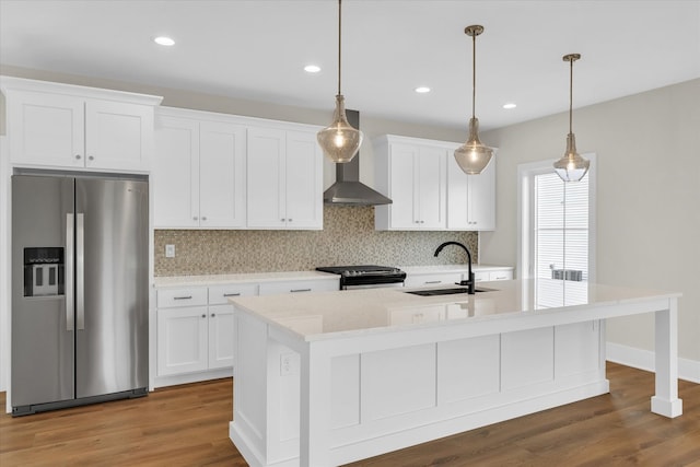 kitchen with wall chimney range hood, stainless steel appliances, tasteful backsplash, hardwood / wood-style floors, and white cabinetry