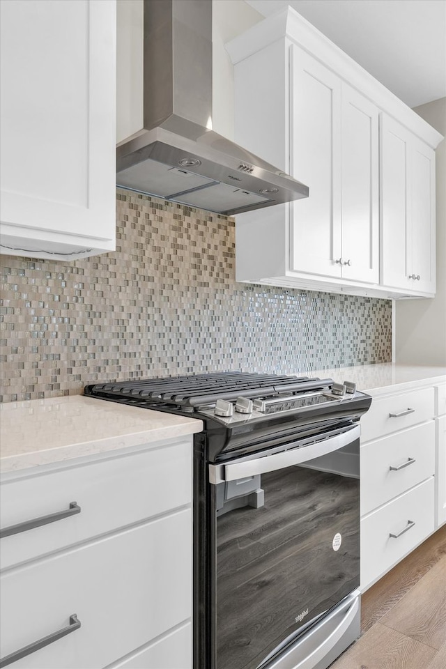 kitchen featuring stainless steel gas range, tasteful backsplash, light hardwood / wood-style flooring, and wall chimney exhaust hood