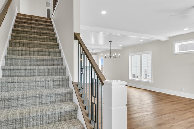 stairway featuring beamed ceiling, an inviting chandelier, and hardwood / wood-style flooring