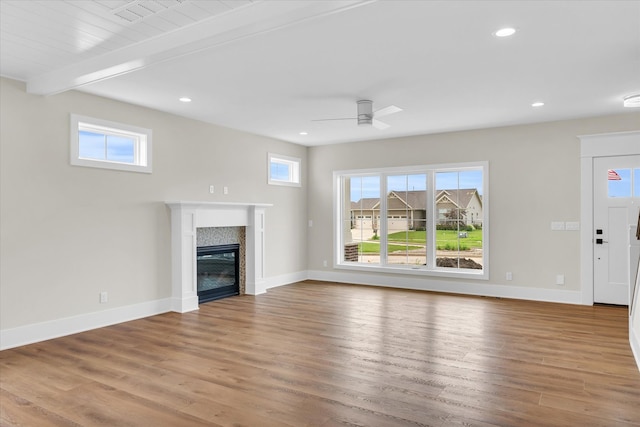 unfurnished living room featuring a premium fireplace, plenty of natural light, and hardwood / wood-style flooring