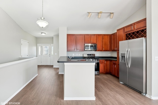 kitchen featuring appliances with stainless steel finishes, hanging light fixtures, sink, vaulted ceiling, and light hardwood / wood-style flooring