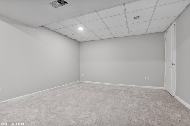 empty room featuring a paneled ceiling and light colored carpet