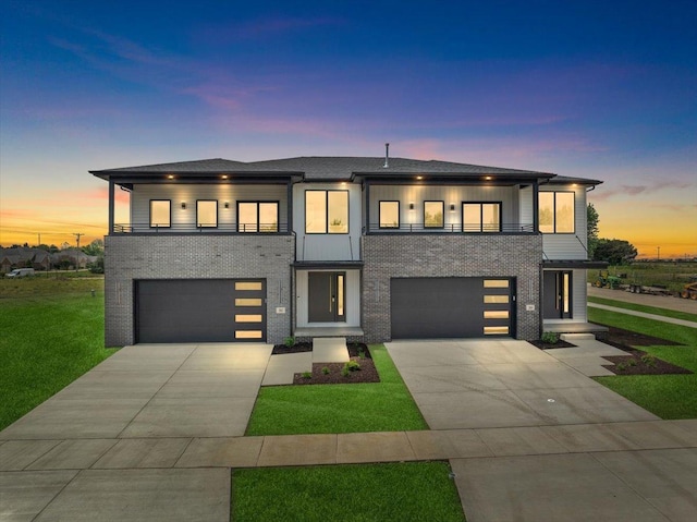 contemporary home featuring a balcony, a garage, and a lawn