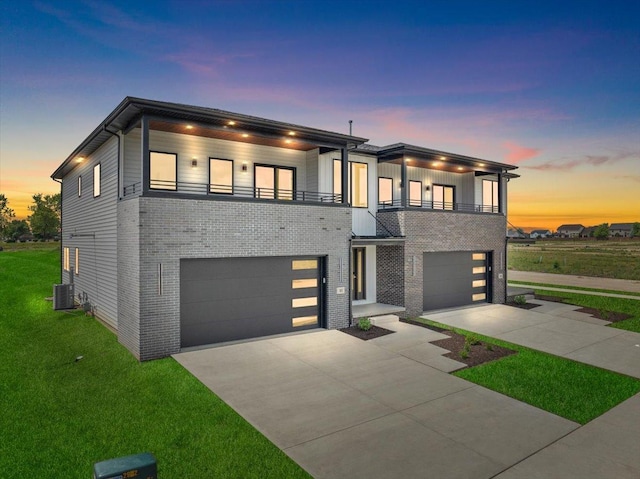 contemporary home featuring cooling unit, a yard, a garage, and a balcony