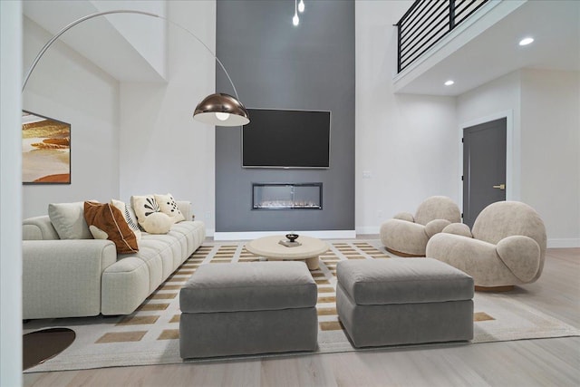 living room with a towering ceiling, hardwood / wood-style floors, and a fireplace