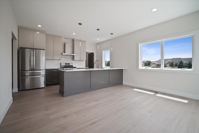 kitchen with gray cabinets, appliances with stainless steel finishes, sink, hanging light fixtures, and wall chimney exhaust hood