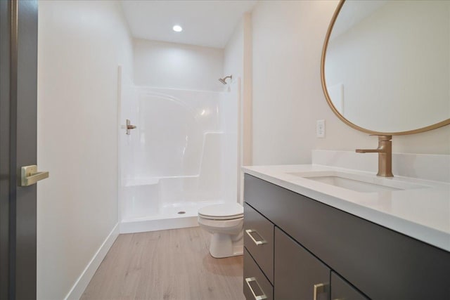 bathroom featuring vanity, hardwood / wood-style flooring, toilet, and a shower