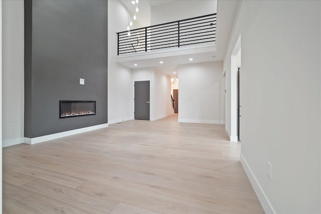 unfurnished living room featuring a towering ceiling and light hardwood / wood-style flooring