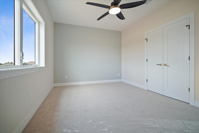 unfurnished bedroom featuring light carpet, a closet, and ceiling fan