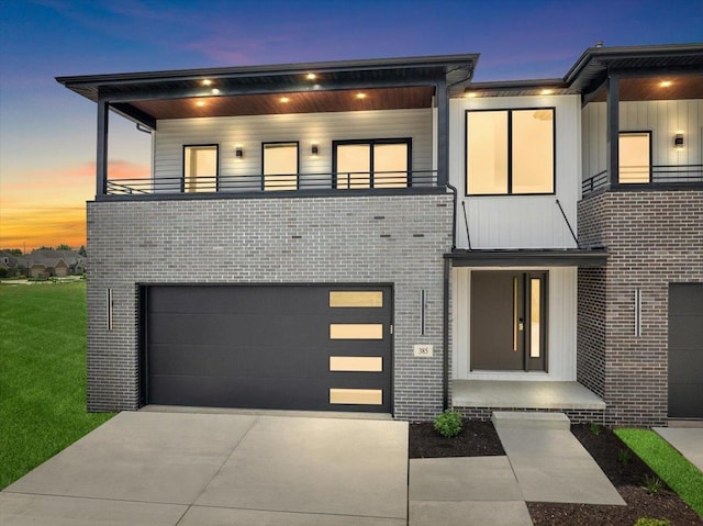 contemporary home featuring a balcony, a garage, and a yard