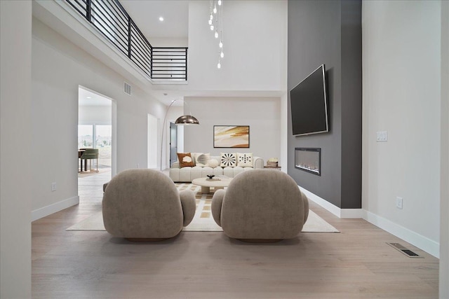 living room featuring light hardwood / wood-style flooring and a high ceiling