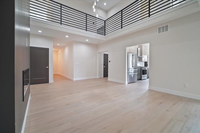 unfurnished living room featuring a high ceiling and light wood-type flooring