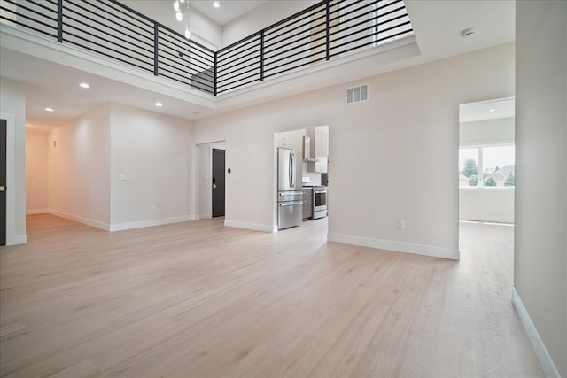 unfurnished living room with a towering ceiling and light hardwood / wood-style floors