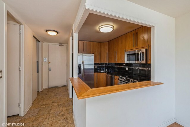 kitchen featuring light tile patterned floors, tasteful backsplash, sink, appliances with stainless steel finishes, and kitchen peninsula