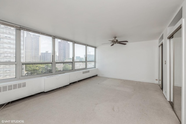 unfurnished sunroom with a ceiling fan and a city view